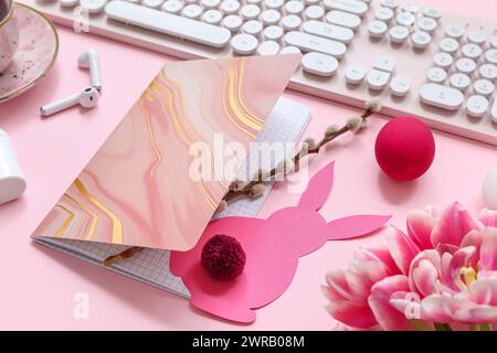Komposition mit Notebook, Tastatur, Ohrhörern und Osterdekor auf rosa Hintergrund, Nahaufnahme Stockfoto