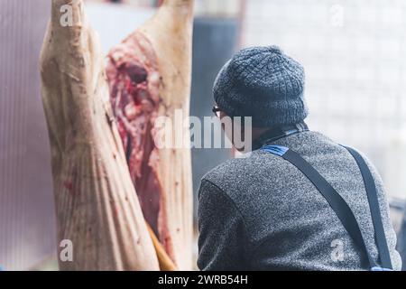 Nahaufnahme der Fleischverarbeitung in der Lebensmittelindustrie, der Arbeiter, der Rohschwein schneidet. Hochwertige Fotos Stockfoto