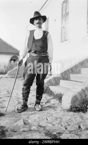 Serbischer Mann mit Hut, Weste, Gürtelhosen und spitzen Schuhen mit Stock, der vor dem Gebäude in Jugoslawien steht, zwischen ca. 1880 und 1924, Serben, Bekleidung und Kleidung, Jugoslawien, 1880-1930, Fotodrucke, 1880-1930., Porträtfotos, 1880-1930, Fotodrucke, 1880-1930, 1 Fotodruck Stockfoto