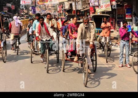 Geschäftige Straßenszene mit vielen Radrikschas und Passanten, Varanasi, Uttar Pradesh, Indien Stockfoto