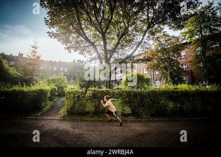 Nikiszowiec, Polen, 14. April 2020: Ein Junge, der durch den grünen Innenhof im Bergbaugebiet Kattowitz, Schlesien, läuft Stockfoto