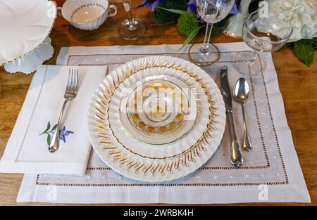 Goldenes und weißes feines Porzellan mit goldgeätztem Kristall auf einem Ostertisch. Stockfoto