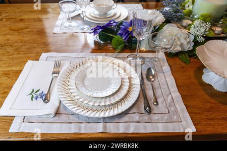 Goldenes und weißes feines Porzellan mit goldgeätztem Kristall auf einem Ostertisch. Stockfoto