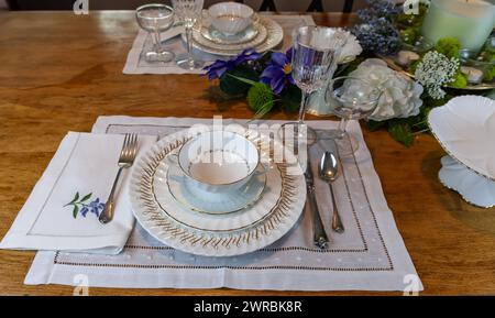 Goldenes und weißes feines Porzellan mit goldgeätztem Kristall auf einem Ostertisch. Stockfoto