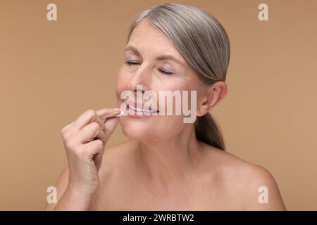 Schöne Frau, die Vitaminpille auf beigefarbenem Hintergrund nimmt Stockfoto