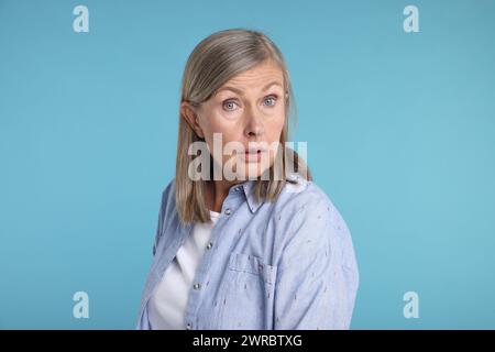 Porträt einer überraschten Seniorin auf hellblauem Hintergrund Stockfoto