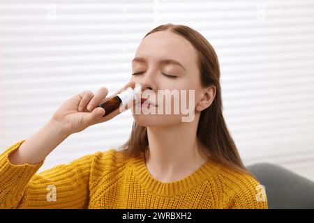 Medizinische Tropfen. Junge Frau mit Nasenspray in Innenräumen Stockfoto