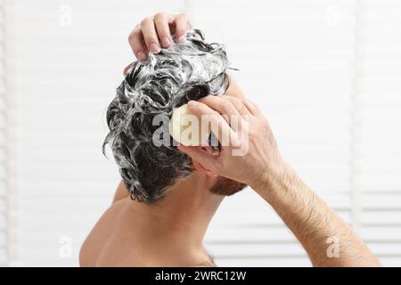 Mann wäscht sich die Haare mit einer festen Shampoo-Bar in der Dusche, Großaufnahme Stockfoto