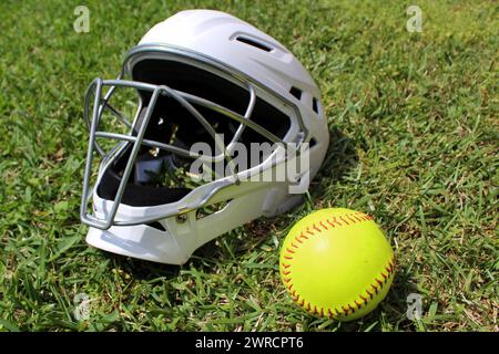Fänger-Helm und Softball auf Gras Stockfoto