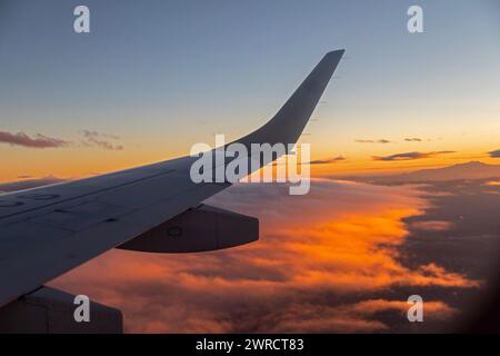 Mexiko-Stadt – ein AeroMexico Connect Embraer Jet fliegt über orangefarbene Wolken, während er sich Mexiko-Stadt nähert. Stockfoto