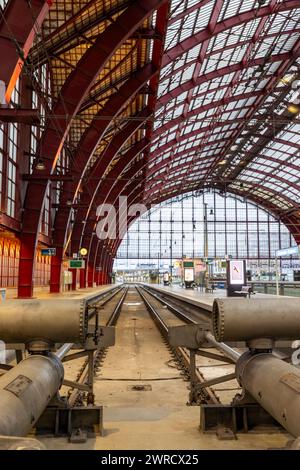 Antwerpen, Belgien, 25. Januar 2024, die architektonische Symmetrie des Innern des Antwerpener Hauptbahnhofs wird aus der Perspektive der Gleise erfasst und führt den Blick auf die ferne Glasfassade. Die Metallkonstruktion der Dachbögen über dem Dach ist ein Beweis für die Gestaltungskraft der industriellen Ära. Die Leere der Gleise sorgt für einen Moment der Stille im Gegensatz zu der üblichen Hektik des Bahnhofs. Strukturelle Symmetrie Im Antwerpener Hauptbahnhof. Hochwertige Fotos Stockfoto