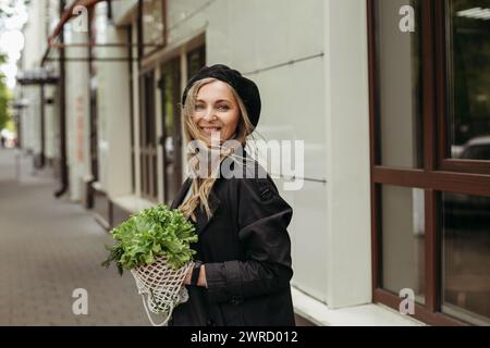 Eine Frau, die steht und einen Haufen Salat vor ihrem Gesicht hält. Stockfoto