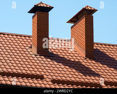 Ein gemauerter Kamin auf einem braunen Metallziegeldach Stockfoto
