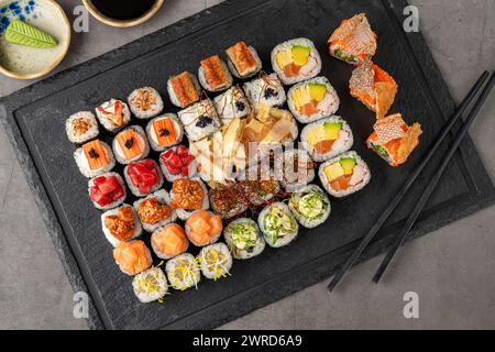 Sushi-Set mit verschiedenen Produkten auf einem schwarzen Steinteller Stockfoto