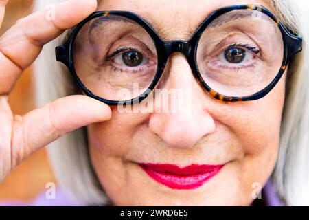 Porträt einer älteren Frau, die eine Brille aufsetzt Stockfoto