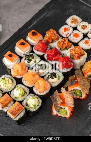 Sushi-Set mit verschiedenen Produkten auf einem schwarzen Steinteller Stockfoto