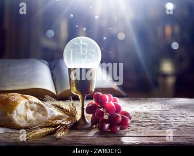 Kommunion - Heiliger Gral mit Fronleichnam und Bibel - Ohren Weizen und Trauben mit Chalice zum Eucharistiefeier - Letztes Abendmahl zur heiligen Messe Stockfoto