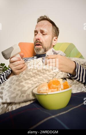 Reifer kranker Mann kümmert sich allein zu Hause im Bett um sich Stockfoto