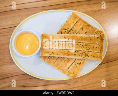 Frische Brotstangen serviert mit Dip-Sauce auf weißem Teller Stockfoto