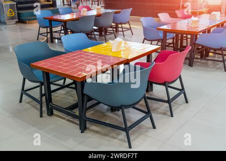 Plastikstühle und Holztische mit farbigen, hellen Keramikfliesen auf Quadraten Stockfoto