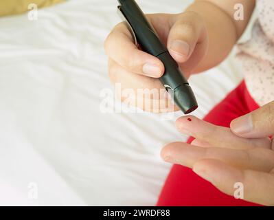 Frau mit lanzettfischchens am Finger, Diabetes Test überprüfung der Blutzuckerspiegel Stockfoto