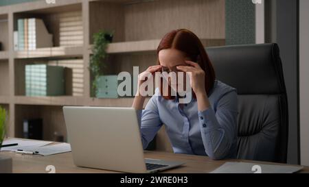 Kaukasische Geschäftsfrau, die mit Laptop im Büro arbeitet, müde von Brille Frau Anstrengung der Augen mit Computerarbeit Brille ablegen und trocken massieren Stockfoto