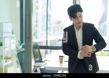 Nahaufnahme eines lächelnden asiatischen Geschäftsmannes, der im Home Office steht, attraktiver Geschäftsmann, der am Arbeitsplatz arbeitet. Stockfoto