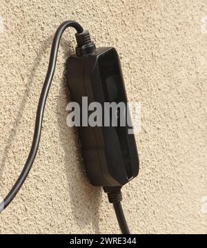 Tragbare Ladestation im Kabel zum Aufladen von Elektroautos an einer grauen Wand. Stockfoto