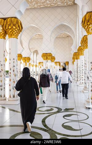 Die Leute besuchen die Scheich-Zayed-Moschee. Traditionell gekleidete Touristenfrau mit schwarzer Burka besucht die große Scheich-Zayed-Moschee in Abu Dhabi, Unite Stockfoto