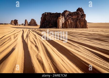 Landschaft von Erg Admer in der Sahara, Algerien. Die Spuren zahlreicher Jeeps treffen sich zu den Felsformationen des La Vache Qui Pleure Sit Stockfoto