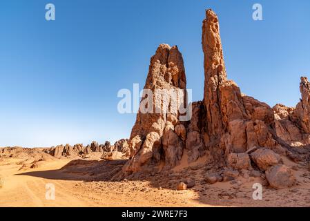 Tadrart-Landschaft in der Sahara, Algerien. Felsige Gipfel aus rotem Sandstein ragen aus dem gelben Sand hervor. Stockfoto