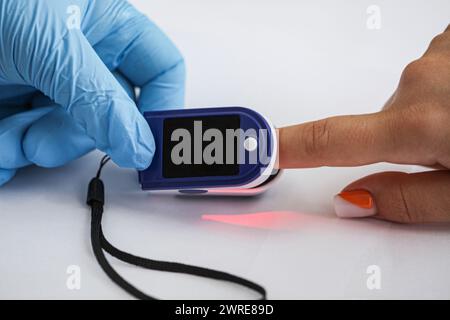 Arzt untersucht Patienten mit Fingertip-Pulsoxymeter im Bett, Nahaufnahme Stockfoto