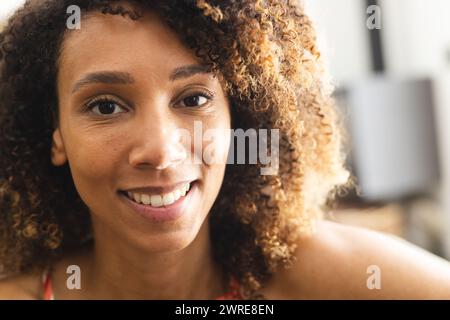 Eine birassische Frau mit lockigem Haar lächelt warm in die Kamera Stockfoto