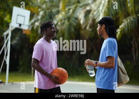 Lächelnde Schwarze, die auf einem Streetballplatz reden Stockfoto