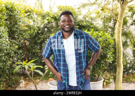 Der Afroamerikaner lächelt breit und steht in einem Garten Stockfoto