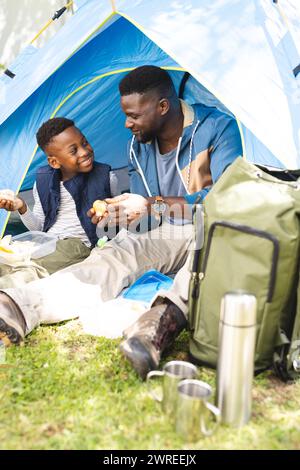 Afroamerikaner Vater und Sohn teilen sich einen Snack in einem blauen Zelt Stockfoto