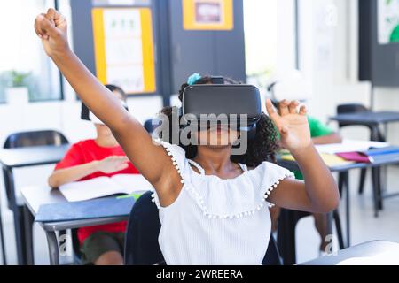 Ein birassisches Mädchen mit dunklen Haaren benutzt ein Virtual-Reality-Headset in einem Klassenzimmer in der Schule Stockfoto