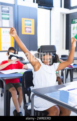 Ein birassisches Mädchen mit lockigem Haar benutzt ein VR-Headset in einem Klassenzimmer in der Schule Stockfoto