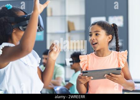 Zwei birassische Mädchen spielen im Klassenzimmer in der Schule mit interaktiven Technologien Stockfoto