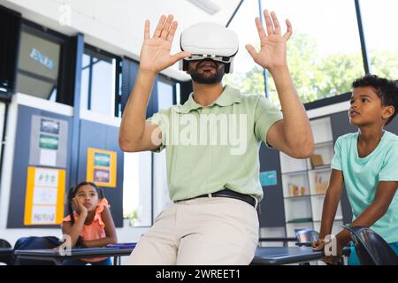 Ein junger asiatischer Lehrer erforscht die virtuelle Realität, indem er ein VR-Headset in einem Klassenzimmer in der Schule trägt Stockfoto