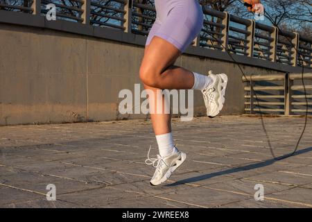 Die Frau in Sportswear springt auf dem Bürgersteig mit dem Seil Stockfoto