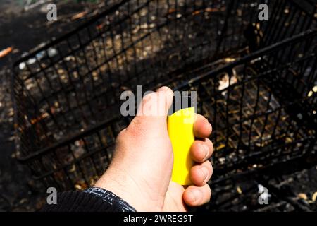 Feuerzeug aus gebranntem Metall in Asche. Die Folgen des Feuers. Nahaufnahme. Stockfoto