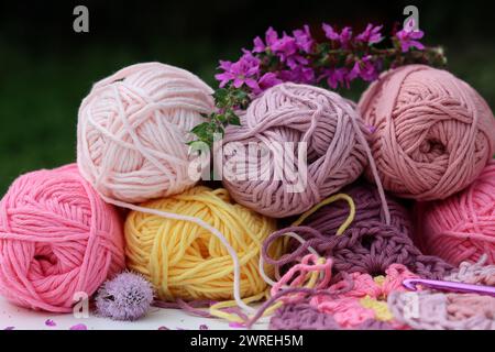 Rosafarbene und violette Garnklötze Nahaufnahme Foto. Wunderschöne weiche Bio-Baumwolle auf einem Tisch. Stockfoto