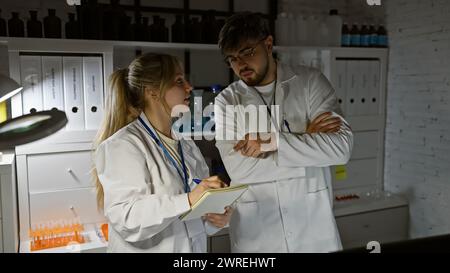 Zwei Wissenschaftler, ein Mann und eine Frau, arbeiten zusammen und diskutieren Forschung im Labor. Stockfoto