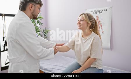 Eine lächelnde Patientin in einer Rehabilitationsklinik hält mit ihrem männlichen Physiotherapeuten in einem Sprechzimmer die Hände. Stockfoto