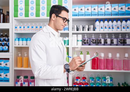 Junger hispanischer Apotheker, der auf einem Dokument in der Apotheke schreibt Stockfoto
