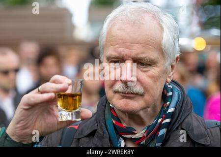 Senior Mann, der skeptisch auf ein Glas Alkohol blickt. Stockfoto