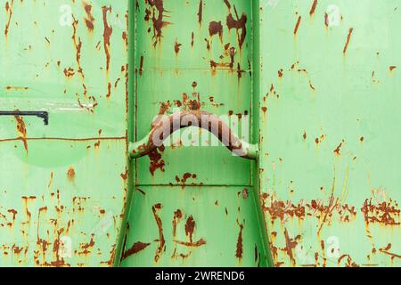 Grüner, gebrauchter, rostiger Behälter zum Sammeln von Recyclingmaterial. Vorderansicht mit dicker Metallstange zur Befestigung am Fahrzeug. Stockfoto