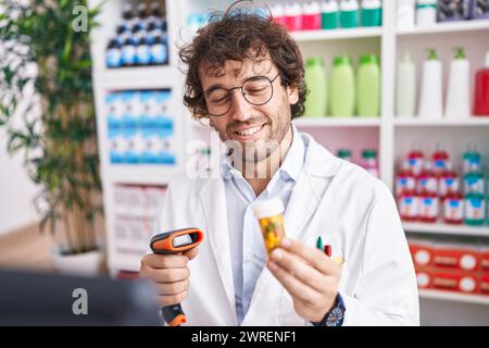 Junger hispanischer Mann Apotheker Scannen Pillen Flasche in der Apotheke Stockfoto