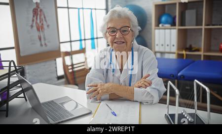 Ältere Ärztin lächelnd in einem gut ausgestatteten Rehabilitationsklinikinnenraum Stockfoto